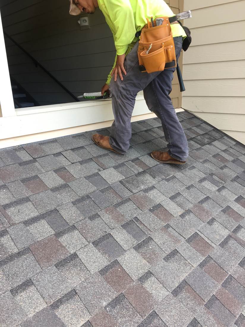 GEJ Roofing crew member installing replacement shingles on an apartment roof