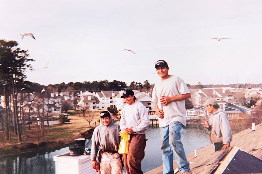 GEJ Roofing crew on a roof overlooking a lake during the early years on the road