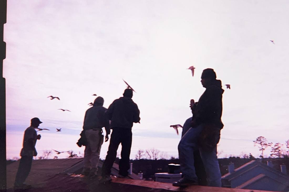 GEJ Roofing crew on a roof at dusk during the early years on the road