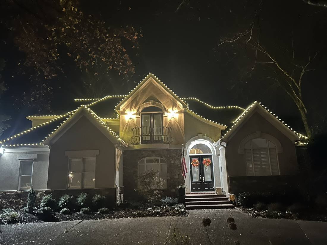 Same Murfreesboro, Tennessee home at night with warm white Christmas roofline lights installed by GEJ Roofing