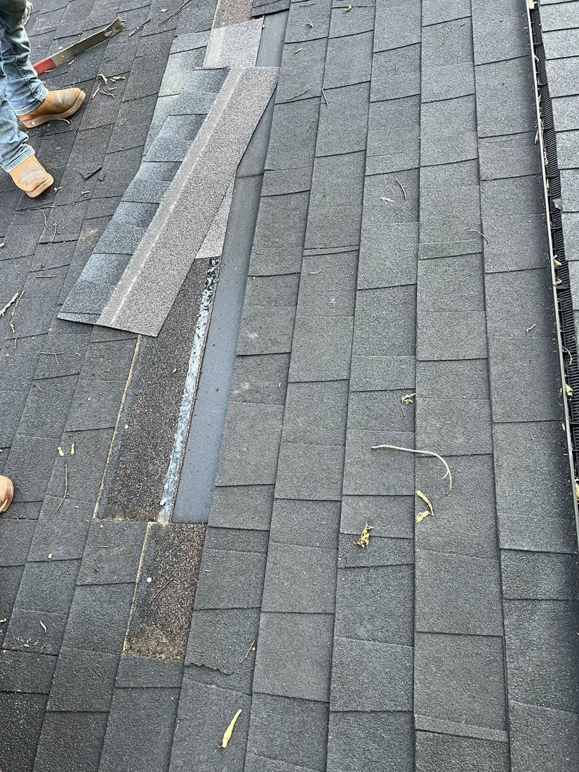 GEJ Roofing crew lifting a damaged shingle during a roof repair after a roof coating failed to stop the leak, Nashville, Tennessee