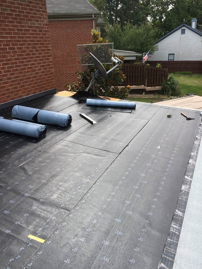 Rolls of insulation board staged on a flat roof deck before installation, Tennessee
