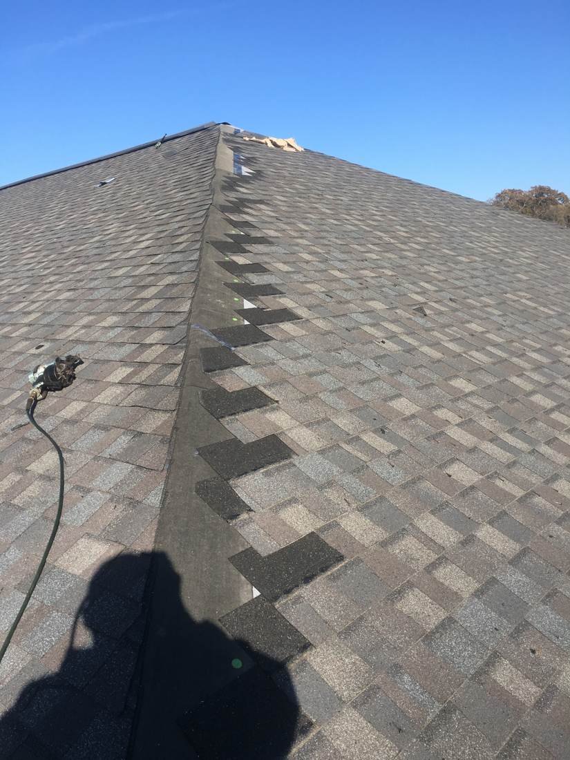 Shingle damage marked with paint dots along a roof ridge for repair at Creekside Elementary School in Franklin, Tennessee