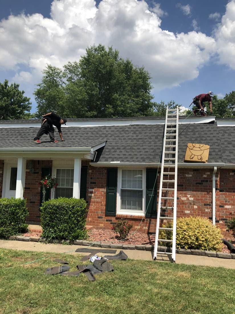 Two roofers working on a hip roof tear-off and reroof on a home in Middle Tennessee
