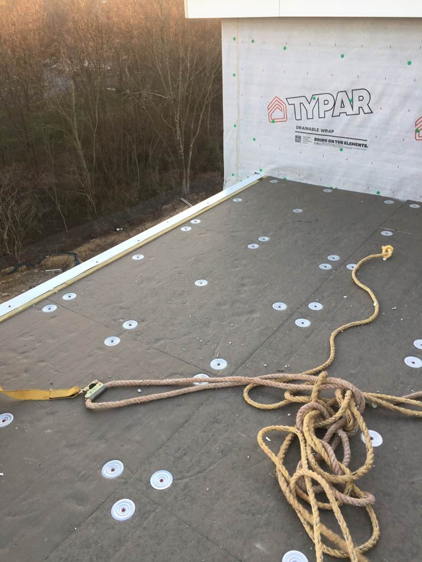Wide view of insulation board and fastening plates installed on a flat roof apartment building in Knoxville, Tennessee
