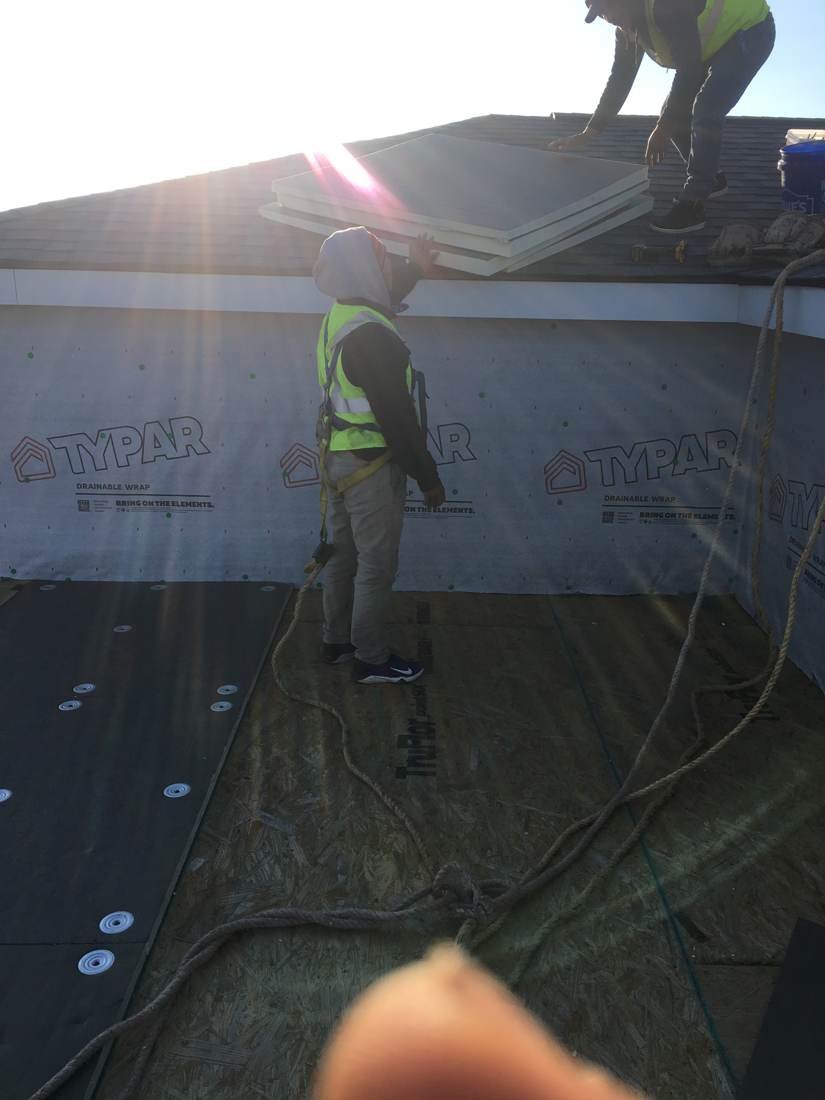 Worker installing synthetic wall wrap at a parapet wall on a flat roof apartment building in Knoxville, Tennessee