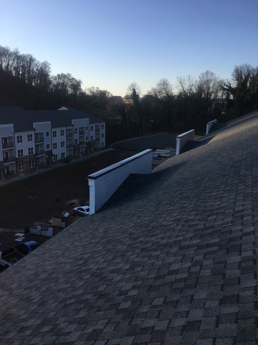 Wide view of a completed shingle roof on an apartment complex in Knoxville, Tennessee, with additional buildings visible