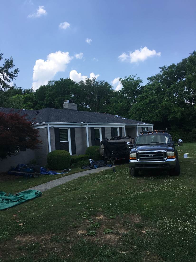 Exterior of a Murfreesboro, Tennessee home mid-roof replacement with tarps and truck on-site