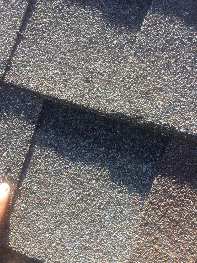 A lifted shingle corner being checked during a GEJ Roofing inspection