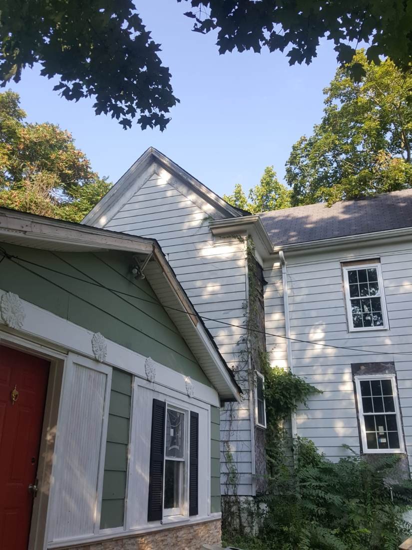 Older farmhouse exterior before a full siding replacement by GEJ Roofing